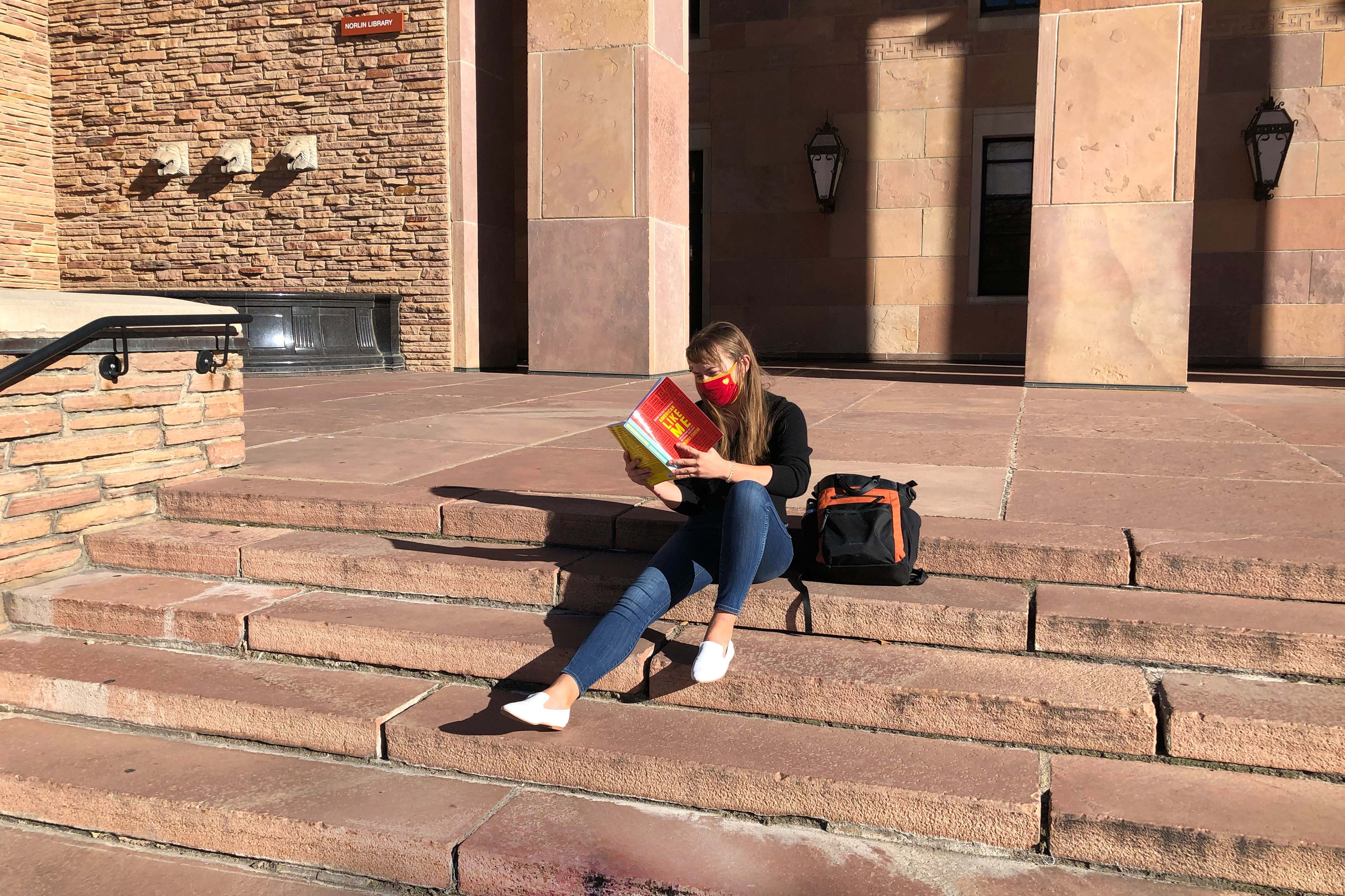 Student reading a book on Norlin steps