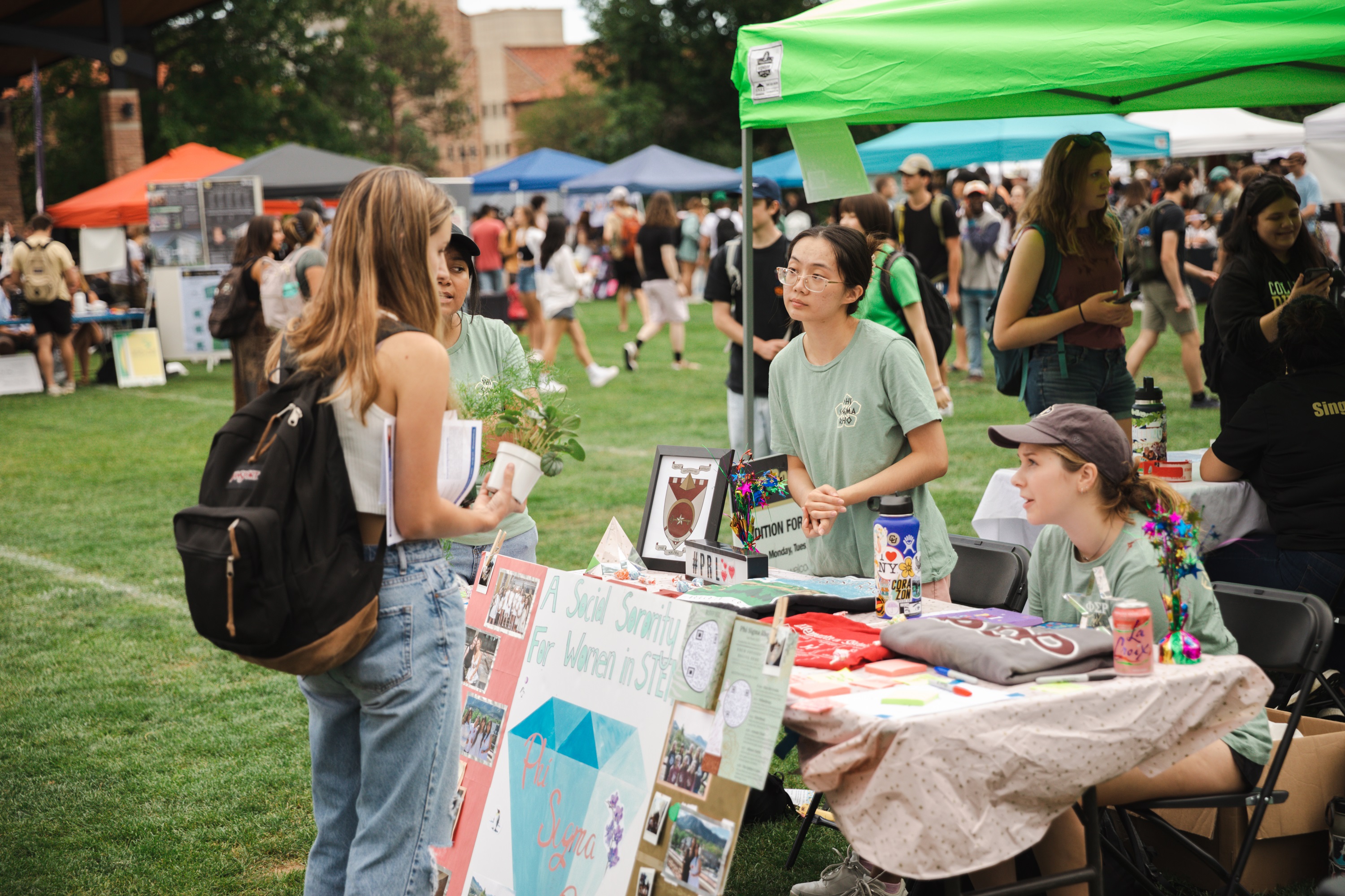 Students at an outdoor fair with umbrellas and tents