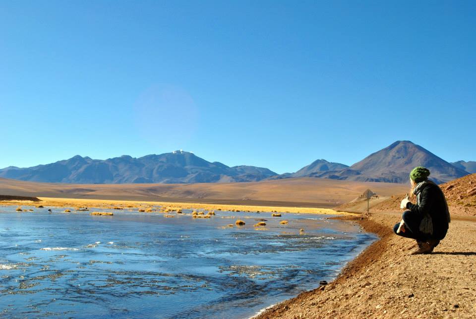 Student squats by the water in Chile