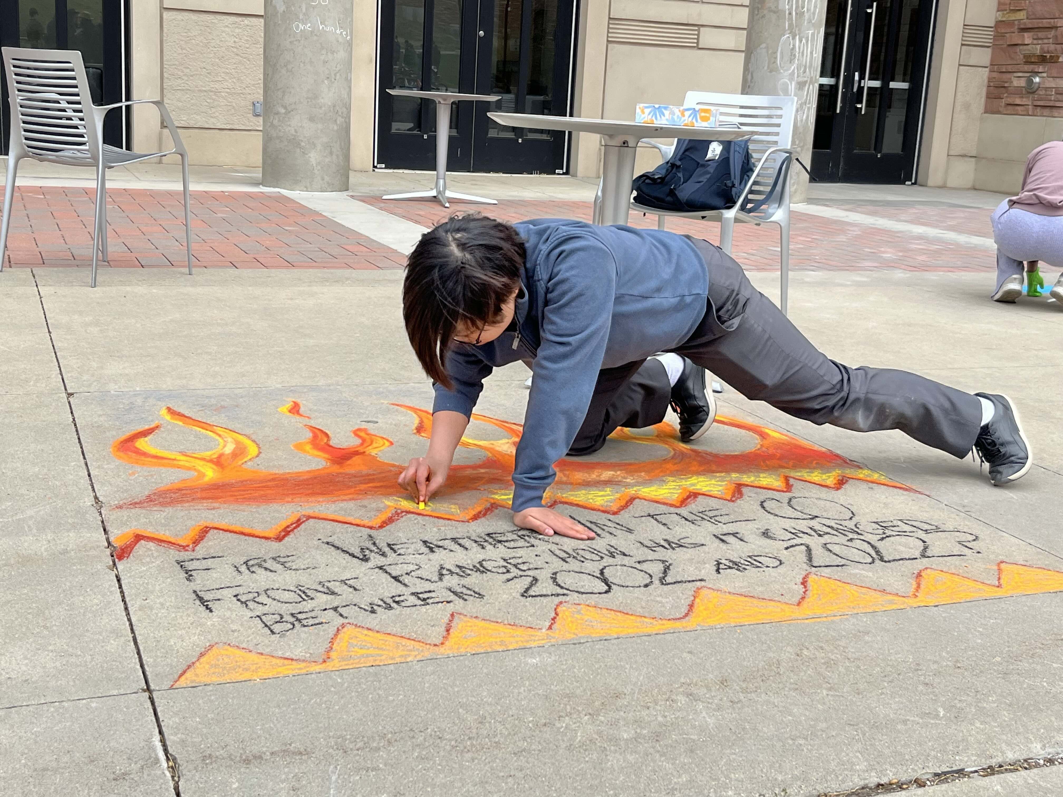 artist illustrating a student's research using sidewalk chalk