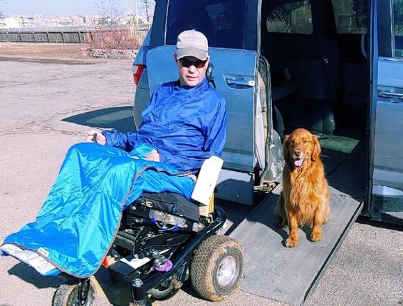 Robert Gray in wheelchair with service dog next to him