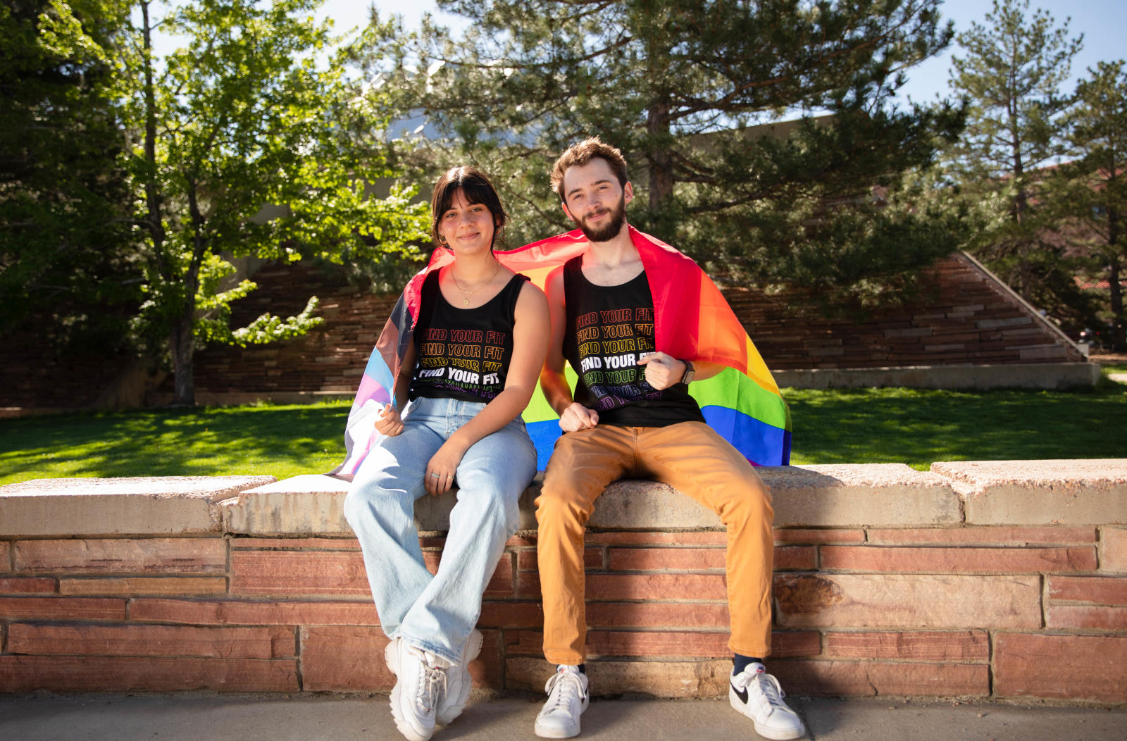 Two students wearing Find Your Fit Pride T-shirts and a Pride Flag