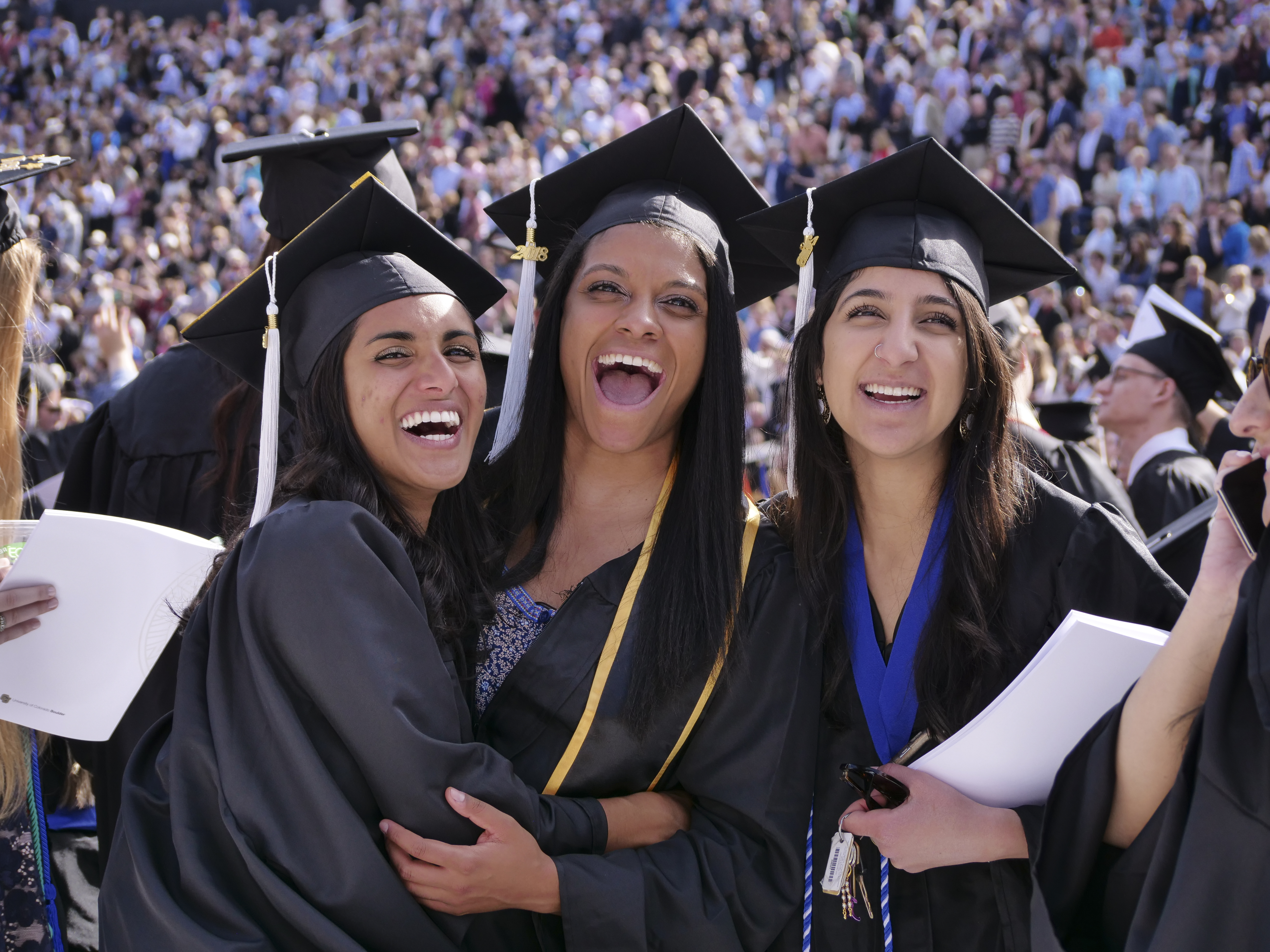 Female students dressed in graduation caps and gowns.