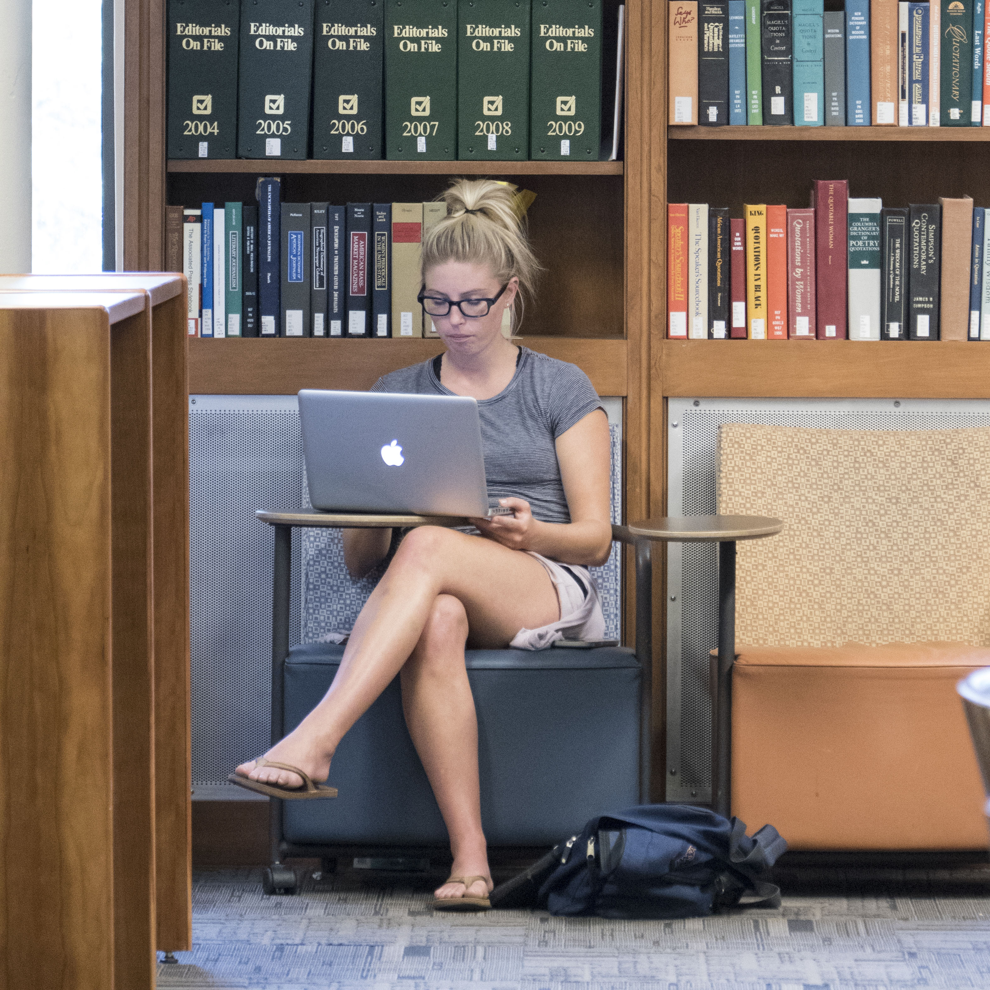 Women studying in library with a laptop.