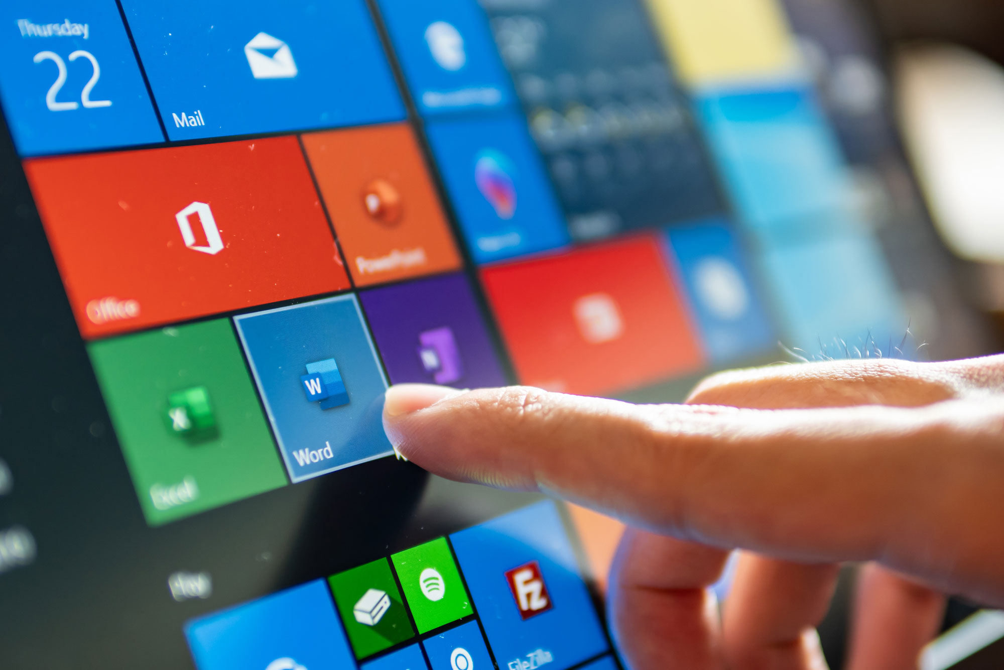 person selecting a Microsoft application on a touch screen