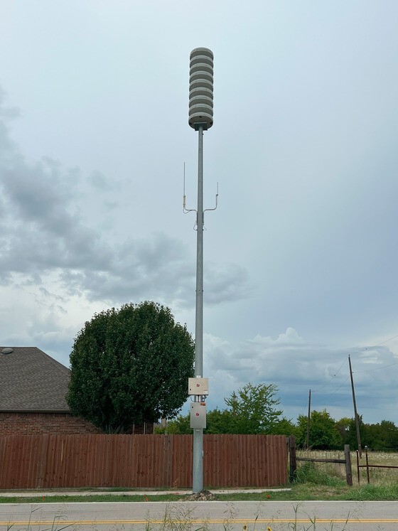 A tall white poll extends from the ground with wider stacked disk shapes at the top. 