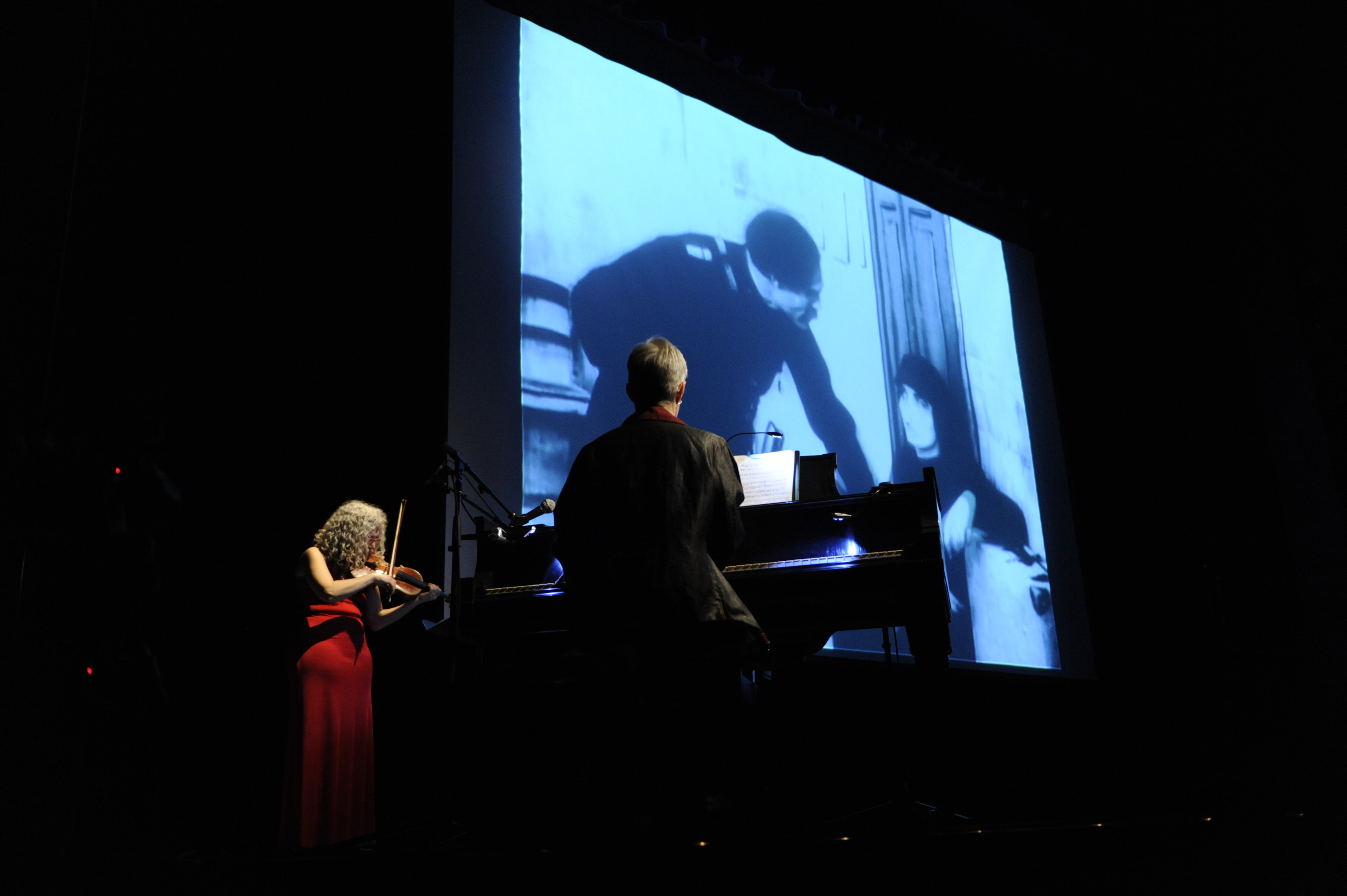Picture of live score performance with black and white film screened behind