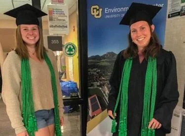 Two graduates wearing green cords