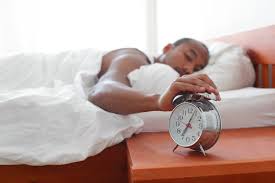 man sleeping reaching for alarm clock
